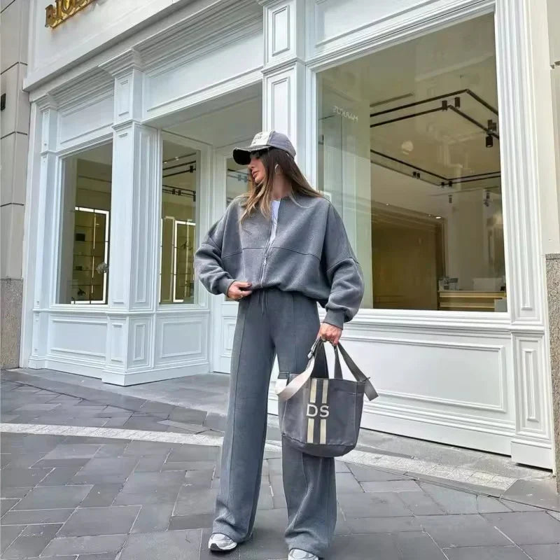 Grey oversized tracksuit set, model standing outside a shop