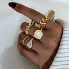 Golden ring set with leaf and stone details, close-up on model's hand