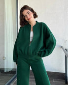 Green zip-up hoodie and joggers set, model smiling on balcony