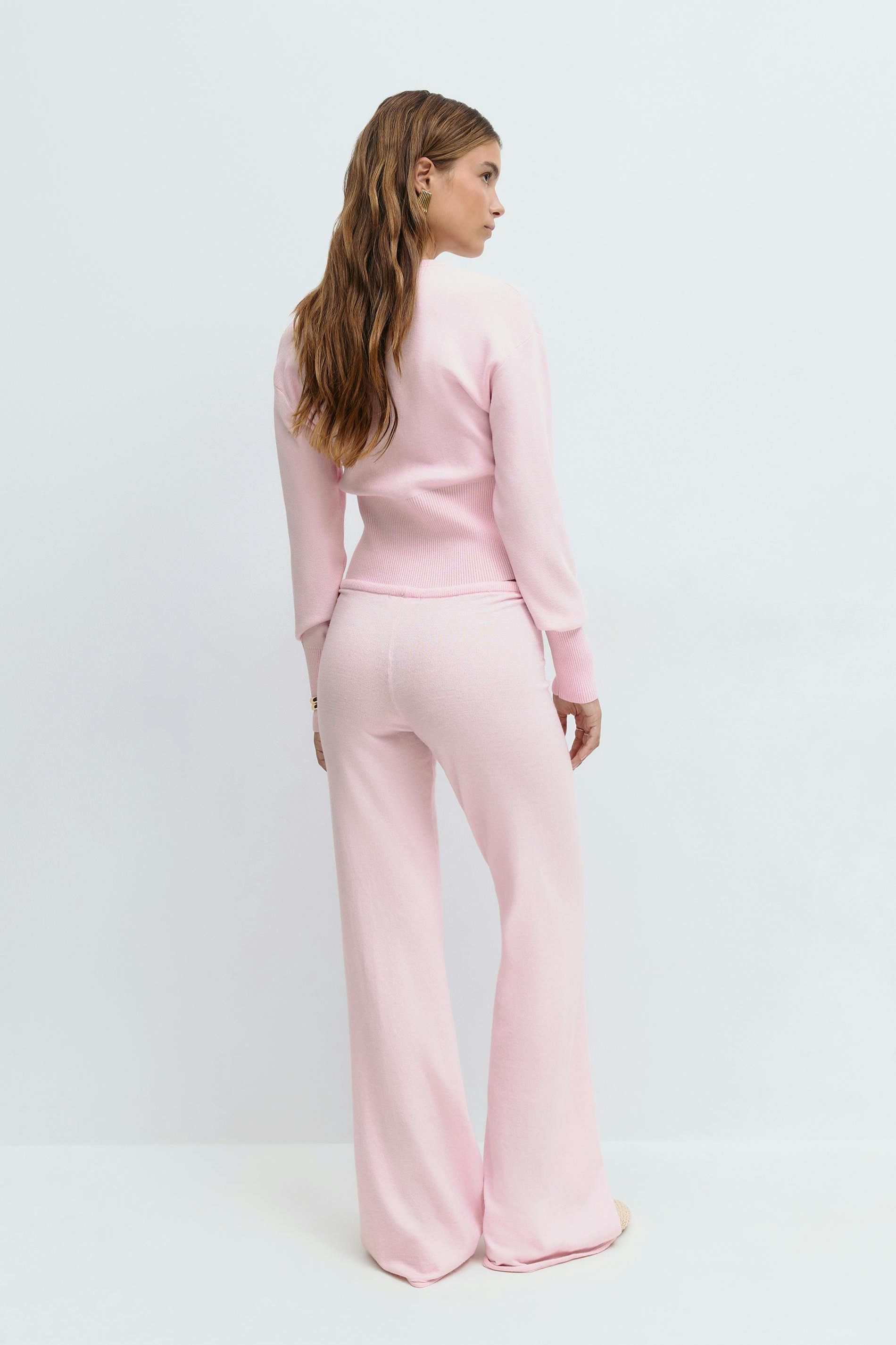 Pink knitted cardigan and trousers set on model, back view