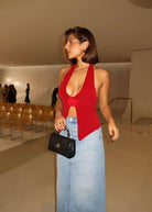 Red halter-neck knit top with rose applique, side view on model
