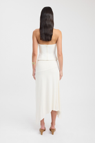 Back view of white bustier top styled with asymmetric midi skirt
