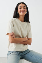 Warm sand cotton crew neck t-shirt, seated pose on model