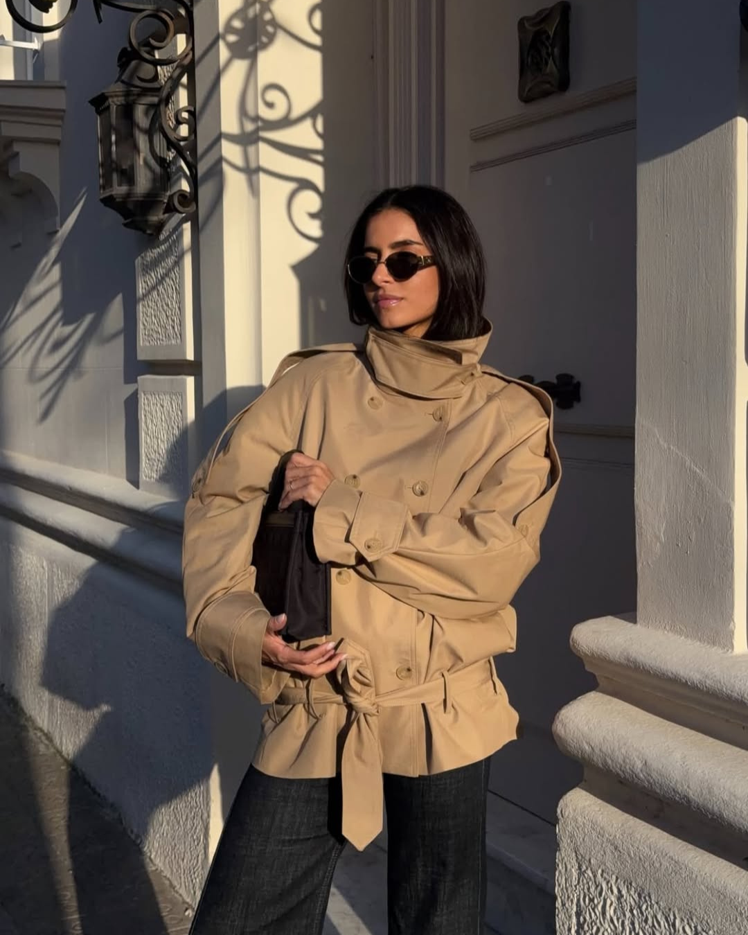 Camel cropped trench coat with wide collar, model in doorway
